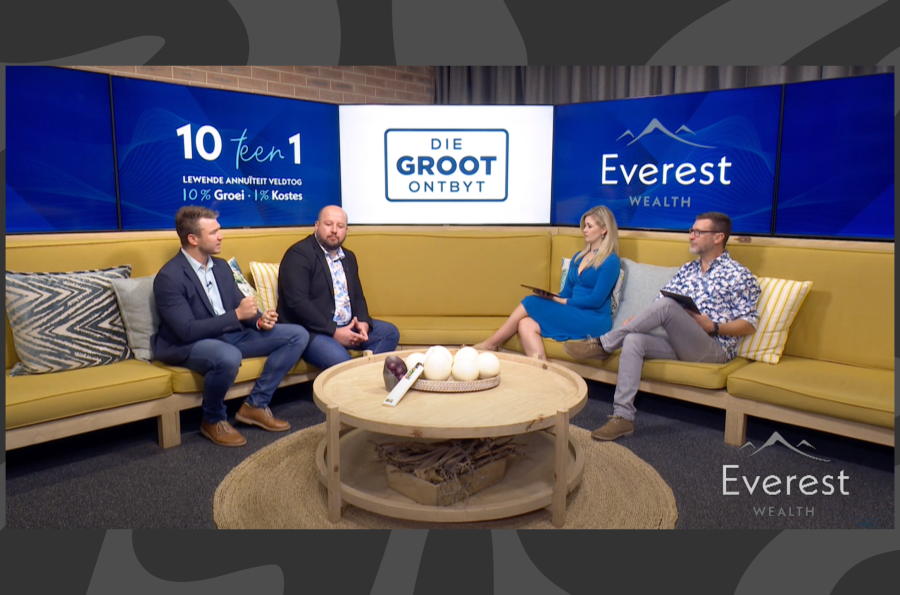 Four people are sitting on yellow couches in a studio set for "Die Groot Ontbyt." Two people appear to interview two others, with blue branding in the background.